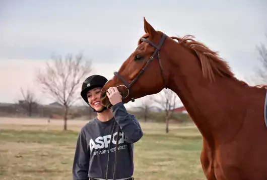 woman smiles with brown horse