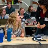 Veterinary students sit at a desk in a large room learning various animal techniques