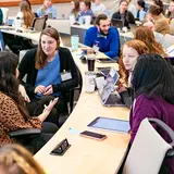 Veterinary students sit at a desk in a large room learning various animal techniques