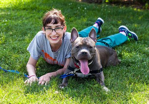 adopter lying on grass with gray pit type dog smiling
