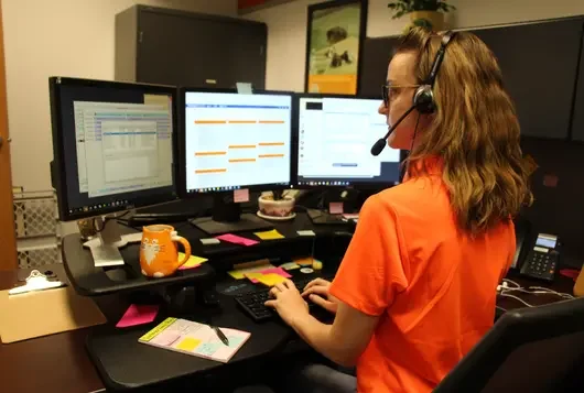 APCC employee at desk in front of three monitors