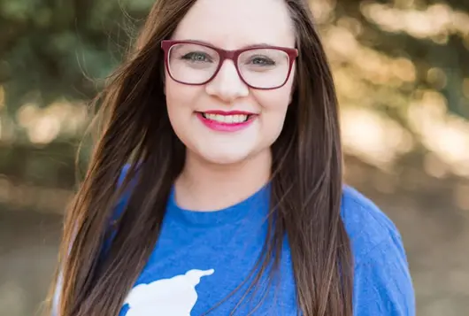 Headshot outdoors of Triniti Halverson wearing blue tee shirt and glasses