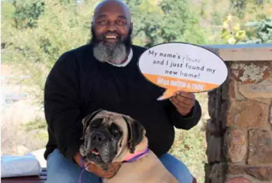 proud man with his dog holds sign that reads that he has adopted the dog