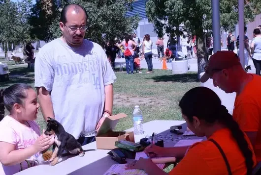 man and child with small dog standing at table during event