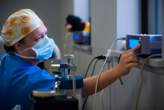 man in blue scrubs and mask working with machine in medical setting