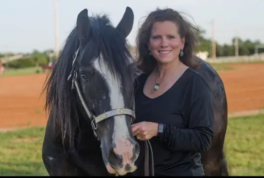 rita stands next to horse