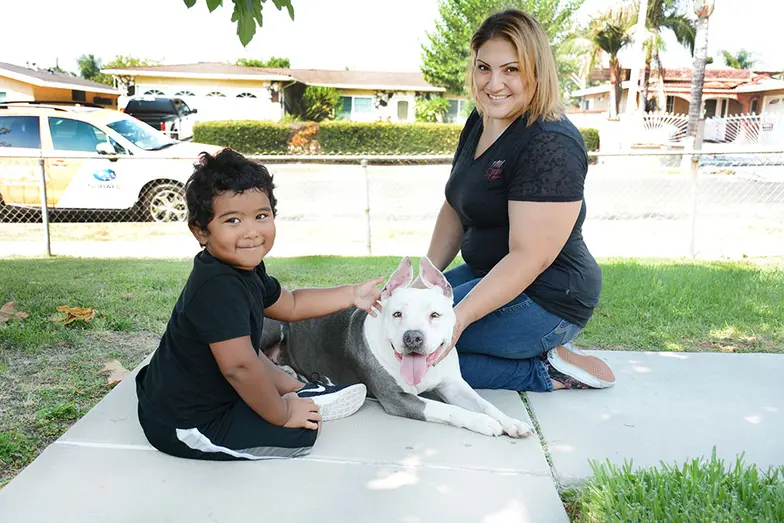 woman and child outdoors with pit type dog