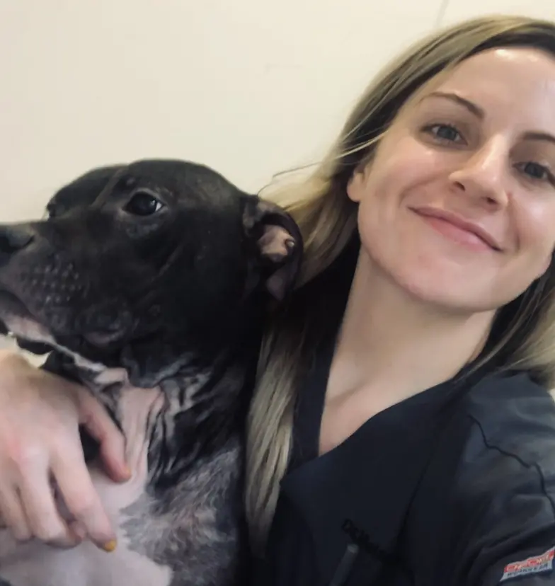 headshot of melanie benetato hugging a black and white dog