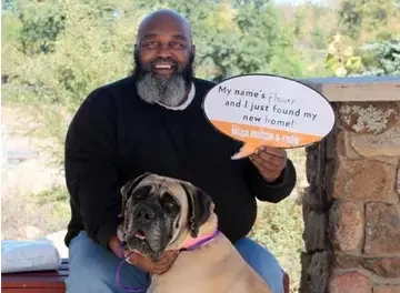 proud man with his dog holds sign that reads that he has adopted the dog