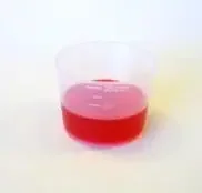 medicine measuring cup of red liquid