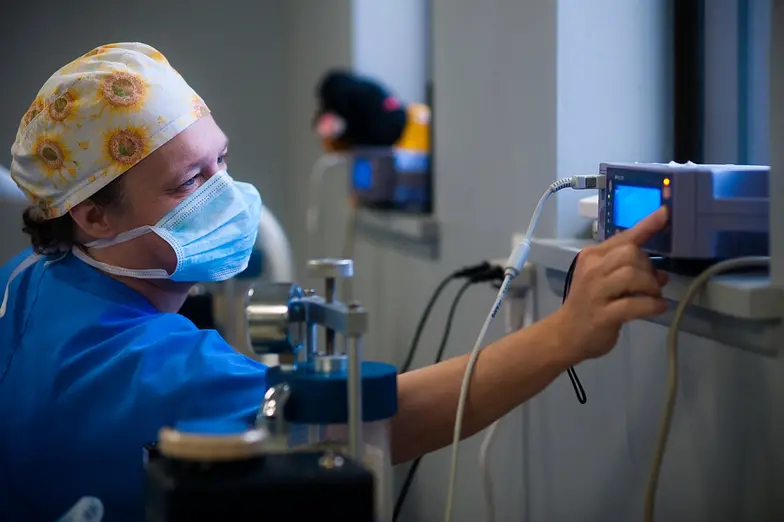man in blue scrubs and mask working with machine in medical setting