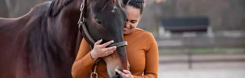 woman with horse outdoors hugging 