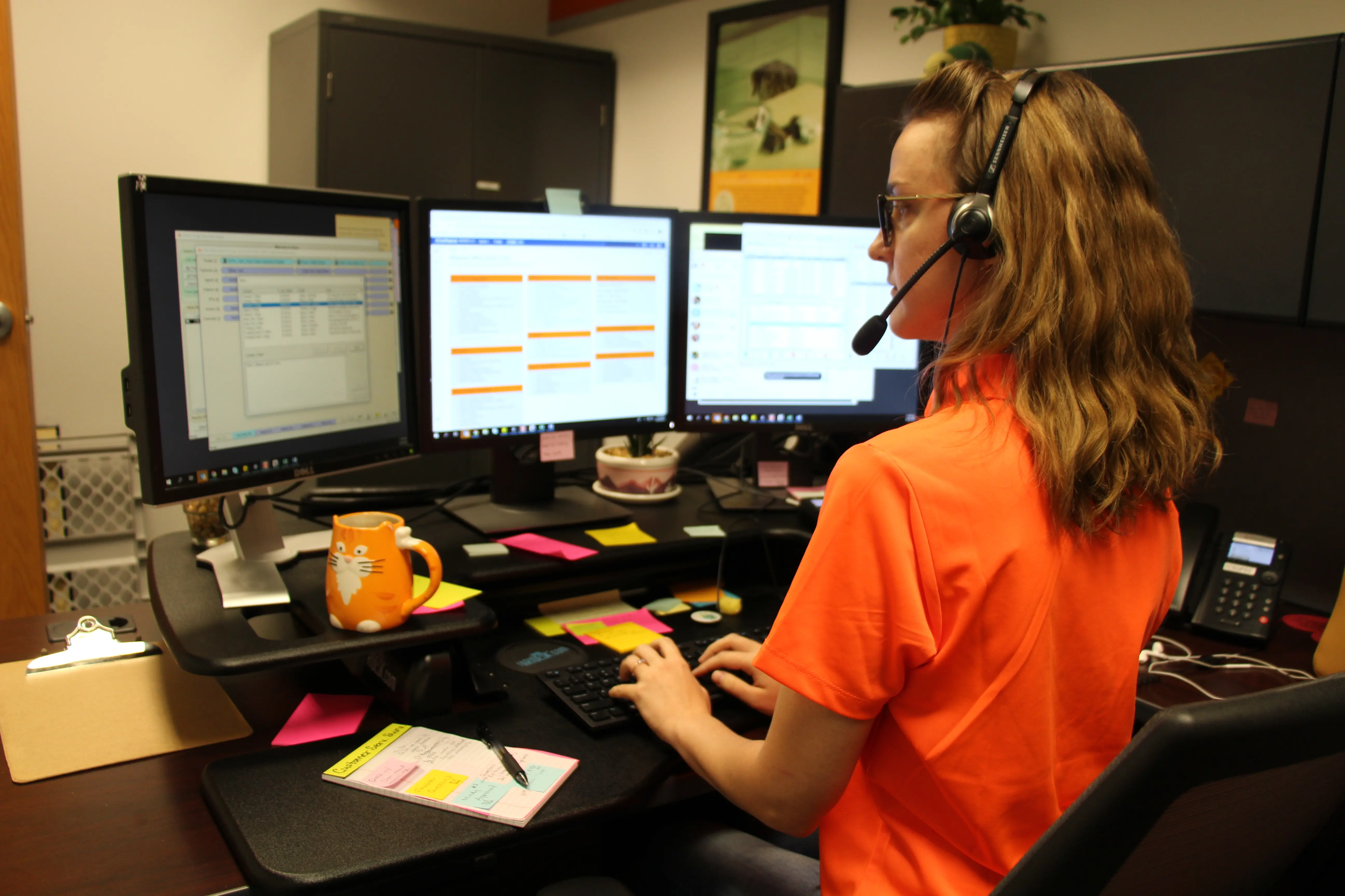 APCC employee at desk in front of three monitors